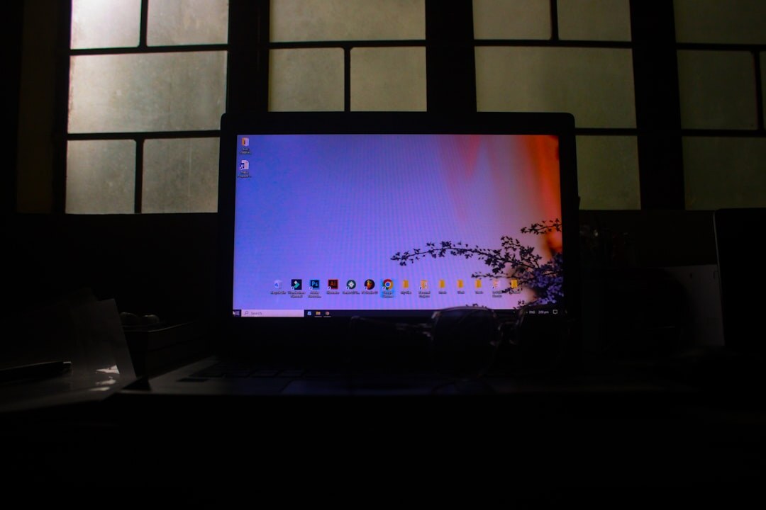 Hands typing on a laptop showing an email inbox in a dim room